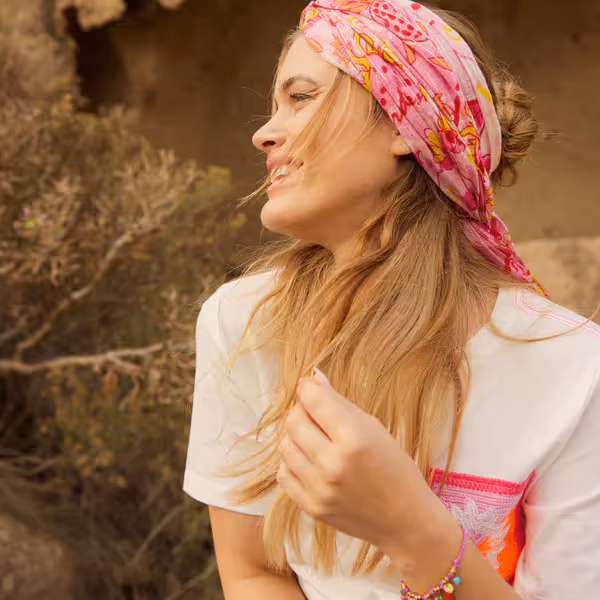 Foto einer Frau mit Haarband im Haar, die auf einem Felsen sitzt
